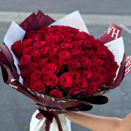 Large bouquet of red roses wrapped in burgundy and white paper