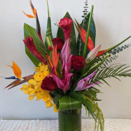 Tropical bouquet with red roses and orchids in a tall glass vase