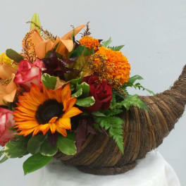 Mixed bouquet in a woven horn-shaped container with a sunflower and roses