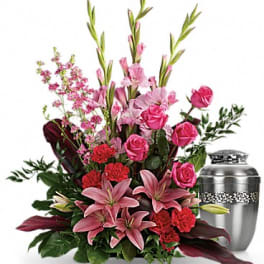 Pink lilies and roses arranged beside a silver urn