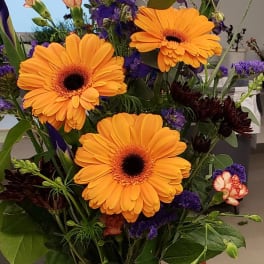 Bouquet of orange gerbera daisies with purple accent flowers