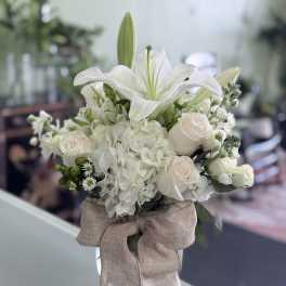 White lily and rose bouquet with hydrangea in a glass vase