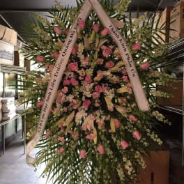 Large standing floral wreath with pink roses and white lilies on a ribboned frame