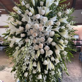 Large white funeral spray with roses and lilies on an easel