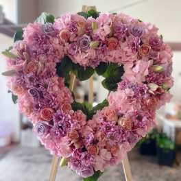 Heart-shaped pink floral wreath on a wooden easel