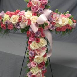 Cross-shaped floral arrangement with roses and orchids on a stand