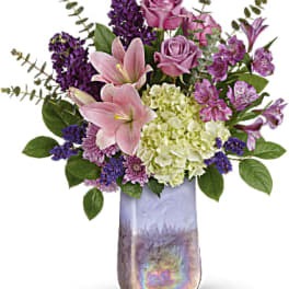Pink and purple flower arrangement in a tall iridescent vase