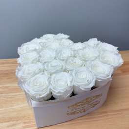 White roses arranged in a rectangular box on a wooden table