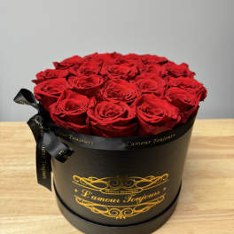 Round black hat box filled with tightly packed red roses