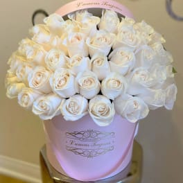Round box of pale ivory roses densely arranged in a light pink hatbox