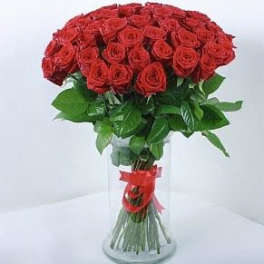 Large bouquet of red roses arranged in a tall clear glass vase with a red ribbon.