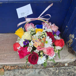 Mixed rose bouquet in a ribboned basket with white daisies
