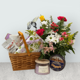 Flower basket with mixed blooms, chocolates, a mug, and a candle
