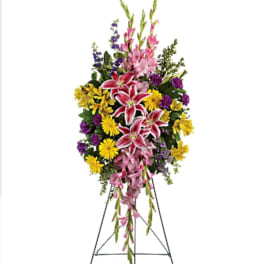 Standing floral spray with pink lilies, yellow daisies, and purple flowers