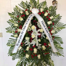 Standing funeral wreath with white roses, lilies, and red carnations