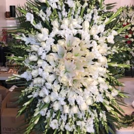 Large white funeral spray with lilies, roses, and orchids
