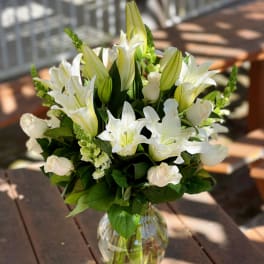 White lilies and pale roses arranged in a clear glass vase