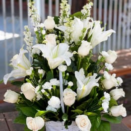 White roses and lilies arranged in a white basket