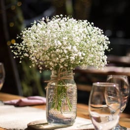 White baby's breath in a glass jar centerpiece on a table