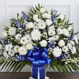 White floral standing spray with blue ribbon and daisies