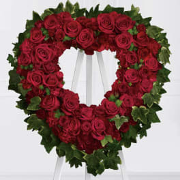 Heart-shaped wreath of red roses on a white stand