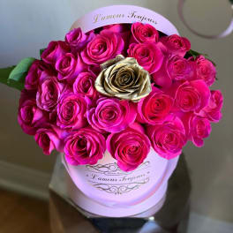 Pink hatbox filled with bright hot pink roses and a single gold rose in the center