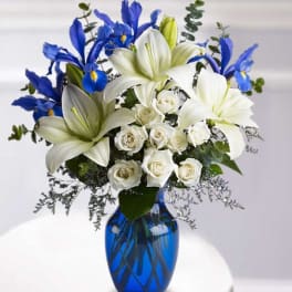 White lilies, blue irises, and white roses in a blue vase
