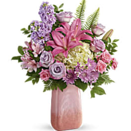 Pink lilies and lavender flowers in a tall pink vase