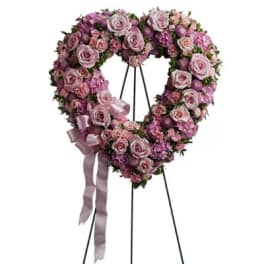 Heart-shaped pink and lavender floral wreath on a stand with ribbon