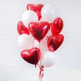 Cluster of red heart balloons and white balloons tied with ribbon