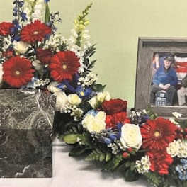 Red, white, and blue floral funeral tribute around a framed photo