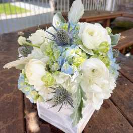 White and pale blue floral arrangement in a square vase