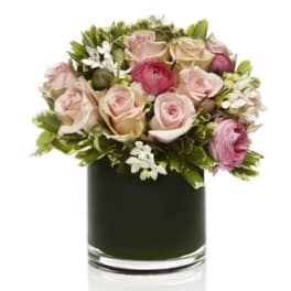 Pink and cream roses arranged in a dark glass vase