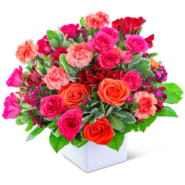 Mixed pink and orange roses with carnations in a white vase