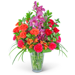 Mixed bouquet of pink orchids, orange roses, and red carnations in a glass vase