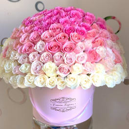 Large dome of pink and cream roses arranged in a round pastel pink hatbox.