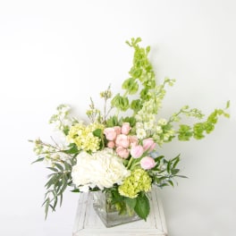 Bouquet of white and pink flowers in a clear square vase