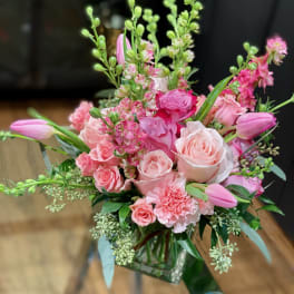 Pink roses and tulips arranged in a clear glass vase