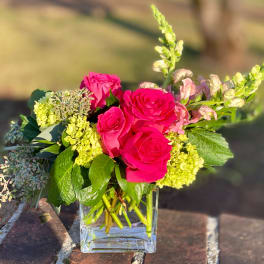 Pink roses and pale green flowers in a clear glass vase
