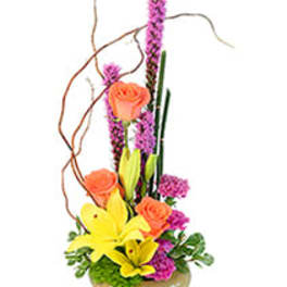 Tall floral arrangement with orange roses and yellow lilies in a low vase
