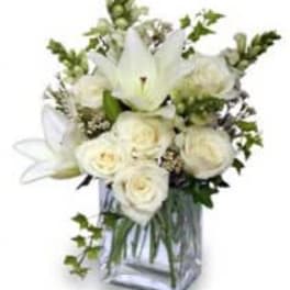 White roses and lilies in a clear square vase