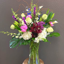 Mixed bouquet in a clear glass vase with pink, white, purple, and blue flowers