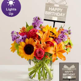 Bright mixed bouquet in a glass vase with a birthday sign