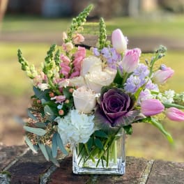Mixed bouquet in a clear glass vase with pink, white, and purple blooms