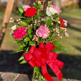 Carnation bouquet in a glass vase with a red ribbon