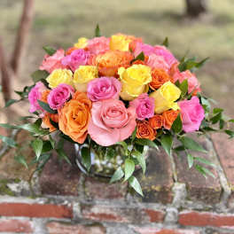 Bouquet of pink, yellow, and orange roses in a glass vase