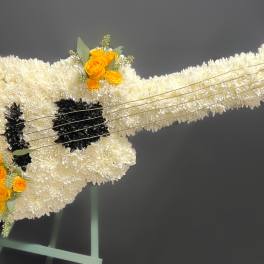 White floral guitar-shaped arrangement with yellow roses and black accents