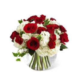 Red roses and white hydrangeas in a clear glass vase