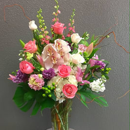 Pink roses and orchids arranged in a clear glass vase