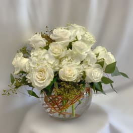 White roses and hydrangeas arranged in a clear glass vase